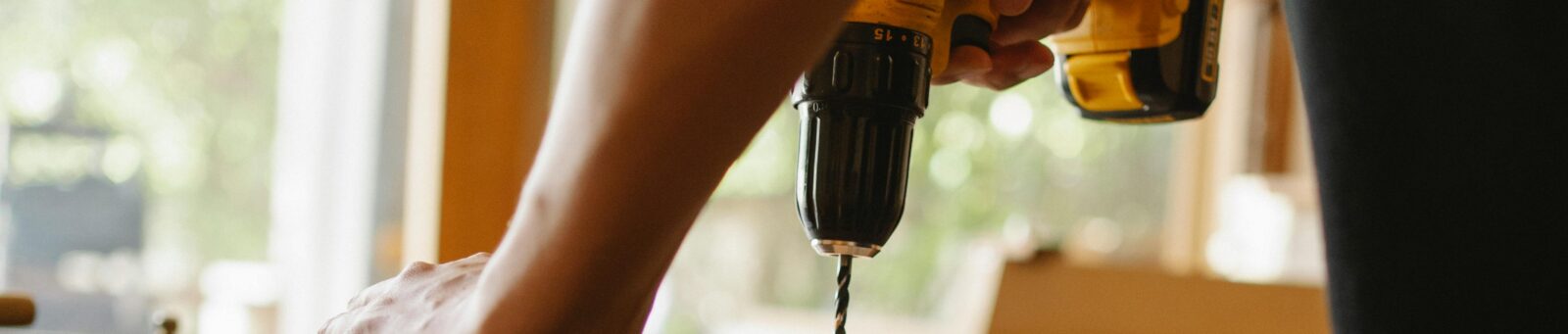 A worker's arm shown drilling wood