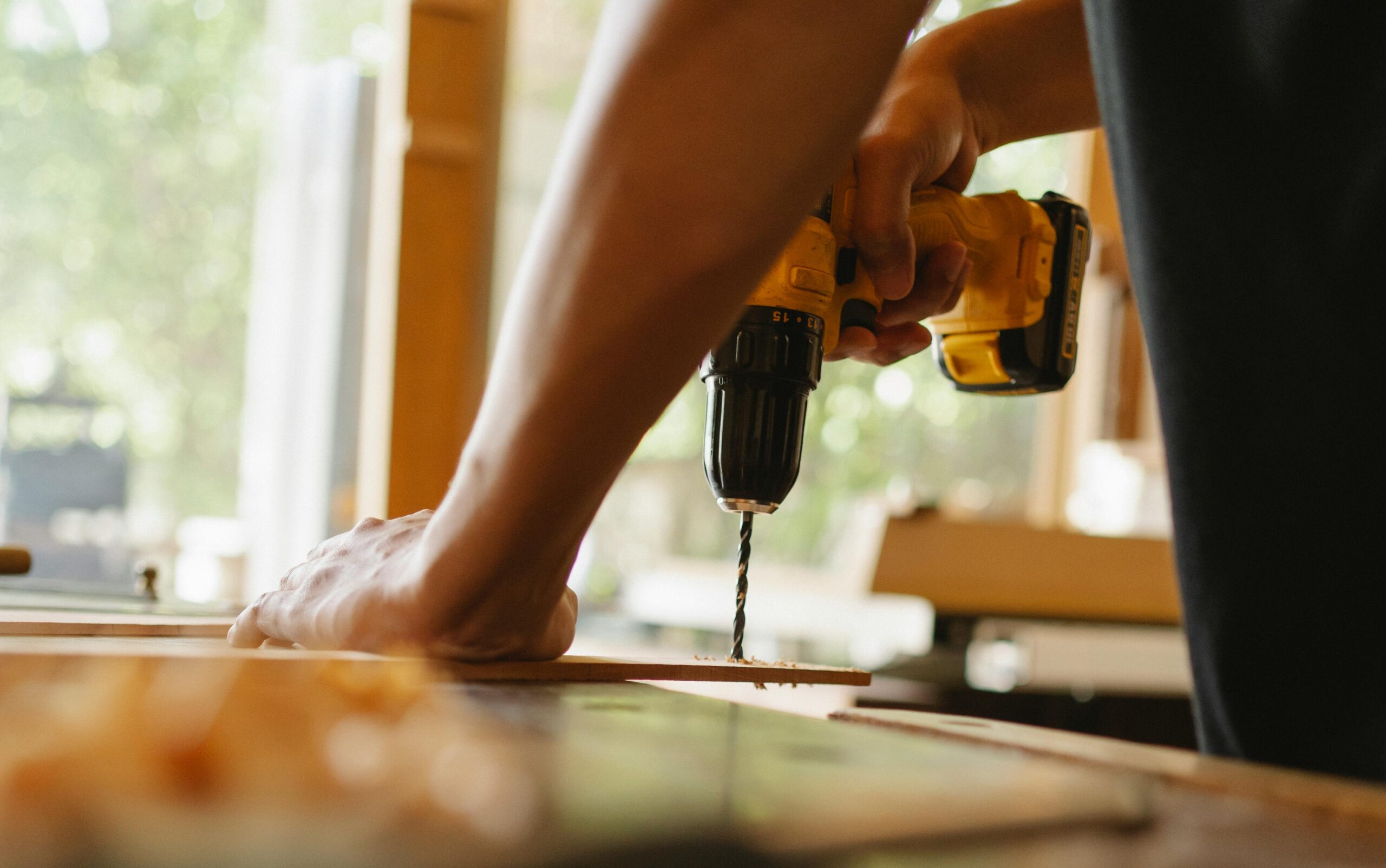 A worker's arm shown drilling wood