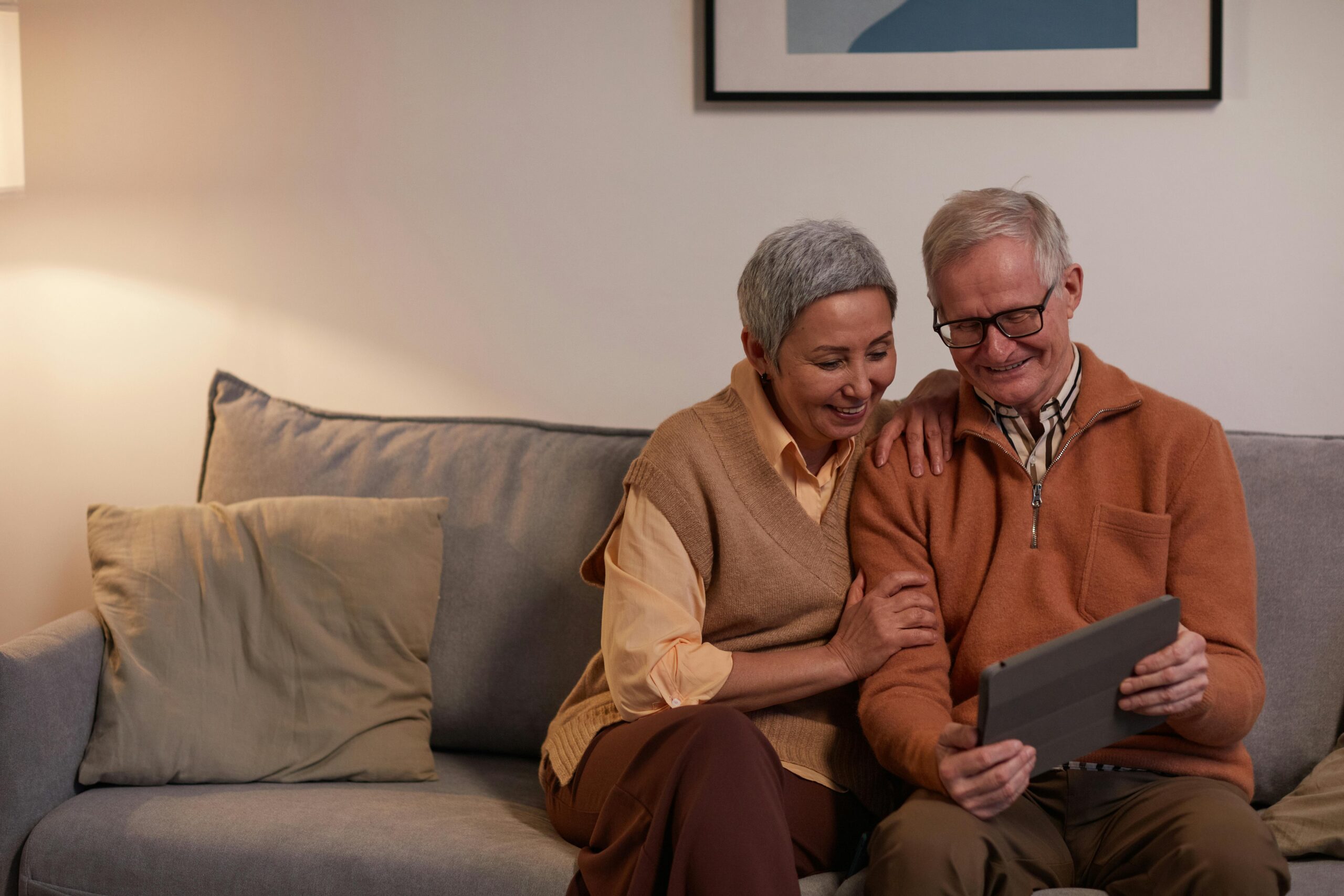 a senior couple looking at a tablet on the couch