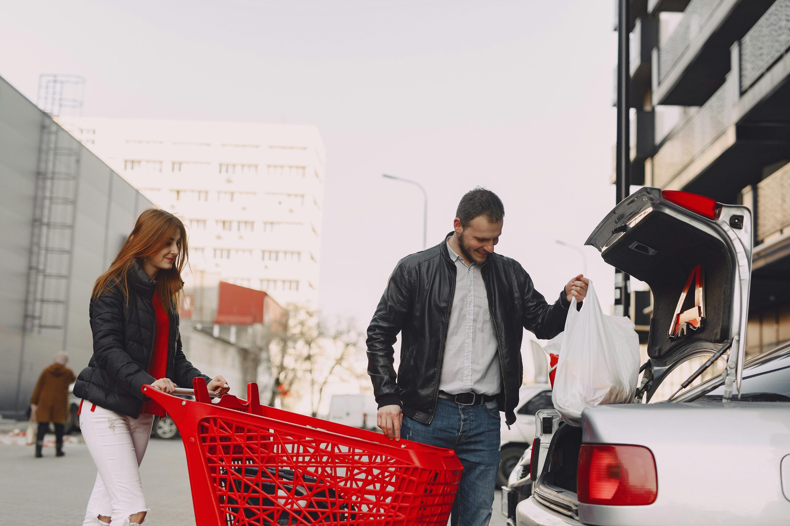 Two people loading shopping bags into the car in a parking lot