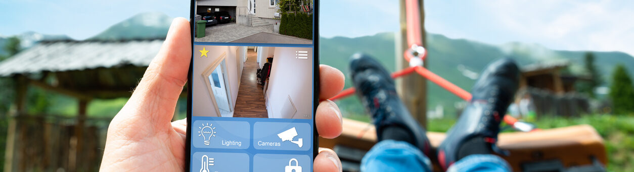 A man uses smart security settings, cameras, lighting, and remote monitoring to protect your home and enjoy greater peace of mind while on vacation.